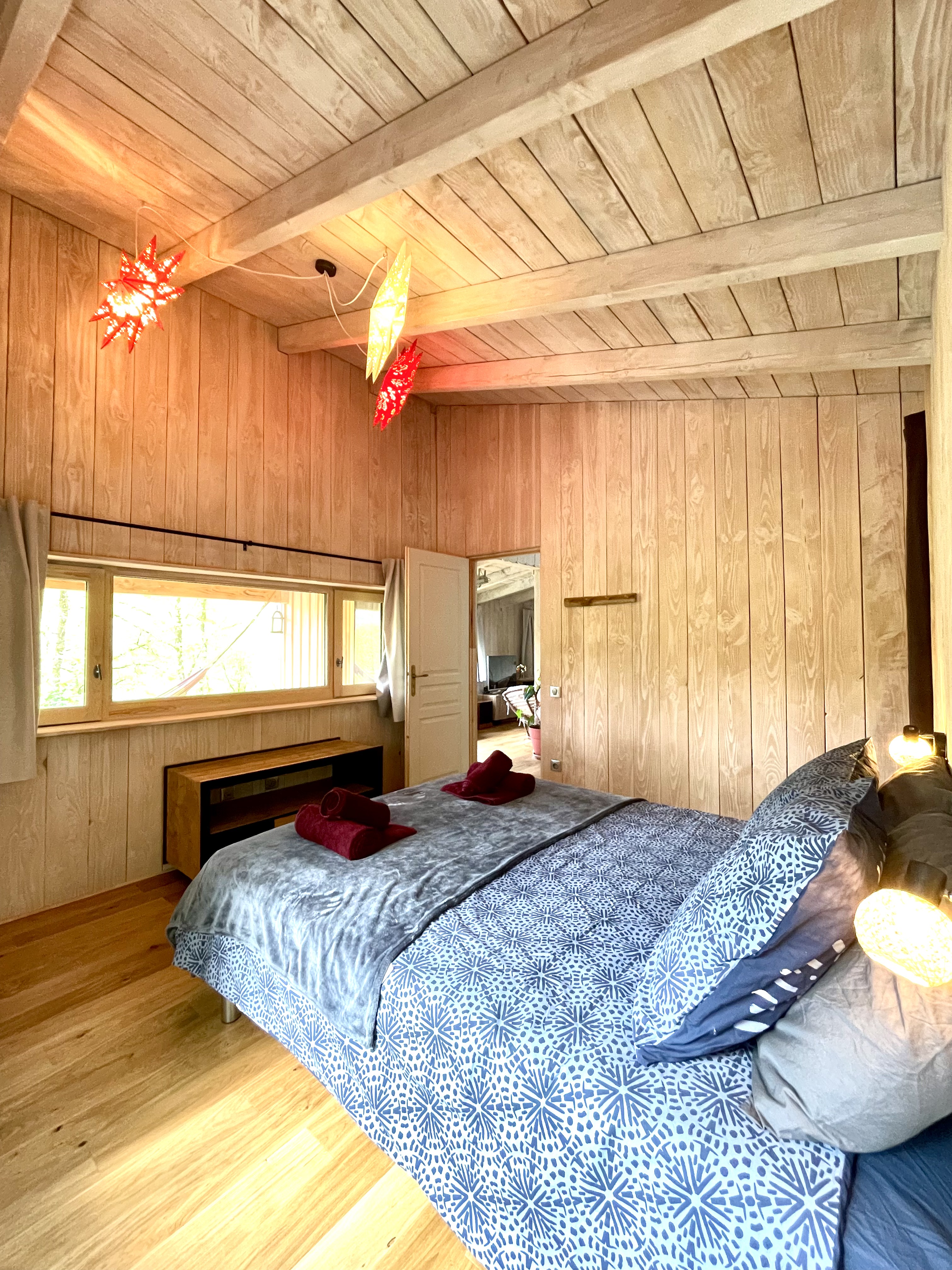 Chambre en bois avec lit double et lumières tamisées à Lalalandes