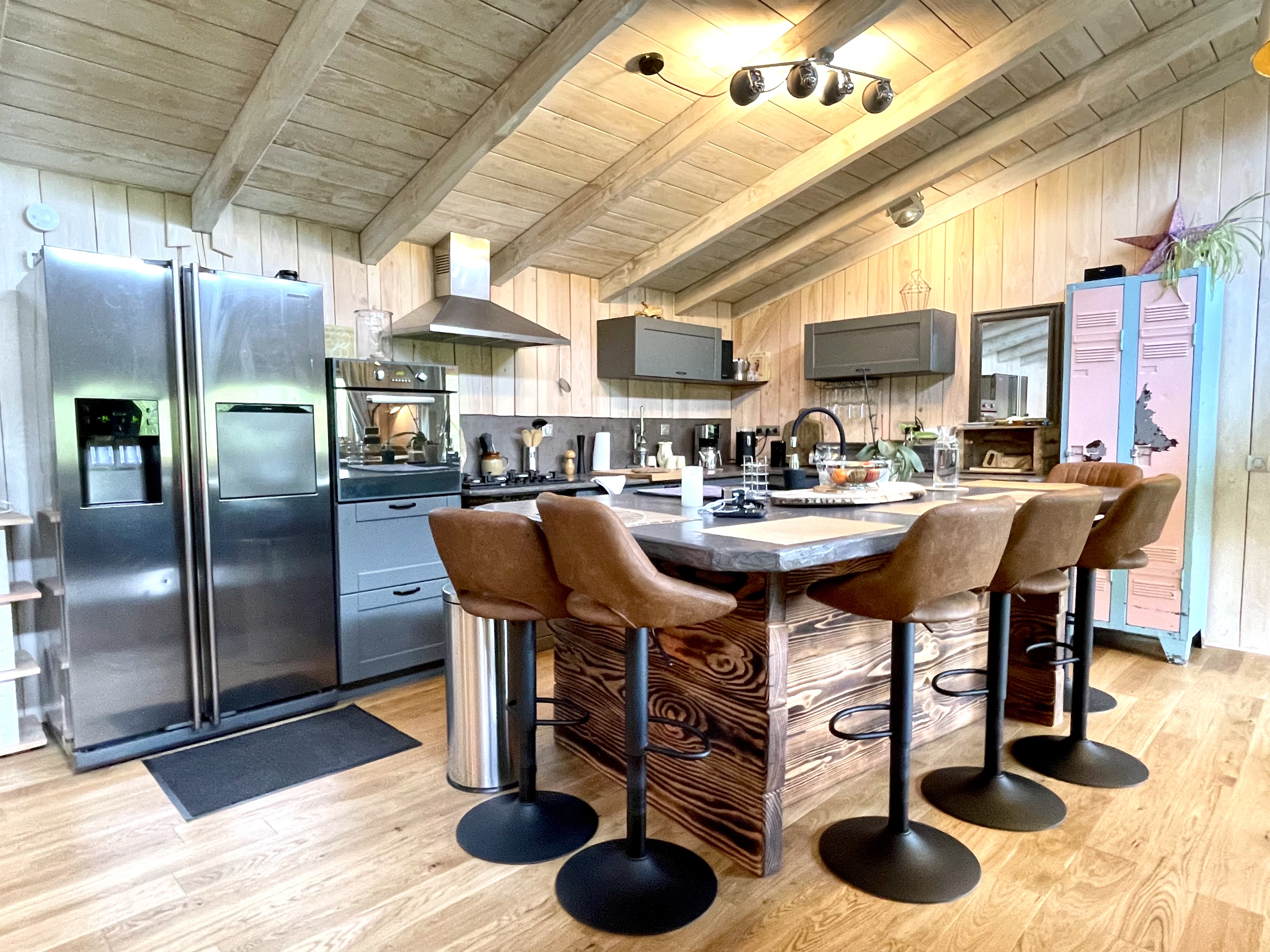 Cuisine ouverte avec îlot en bois brut et chaises de bar à Lalalandes